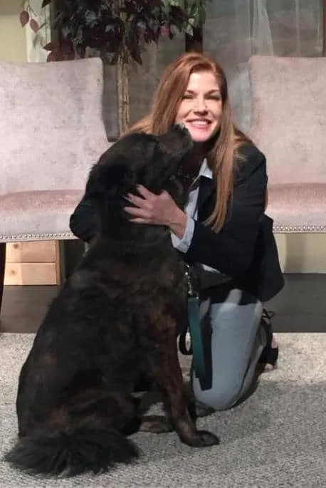 Dr. Tammy Bradshaw-Scott hugging a large black dog
